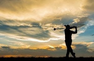 a man golfing in the sunset