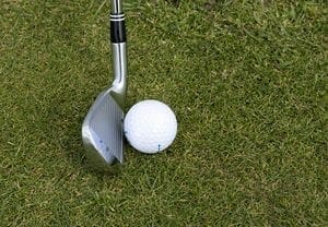 a putter and a golf ball in the green