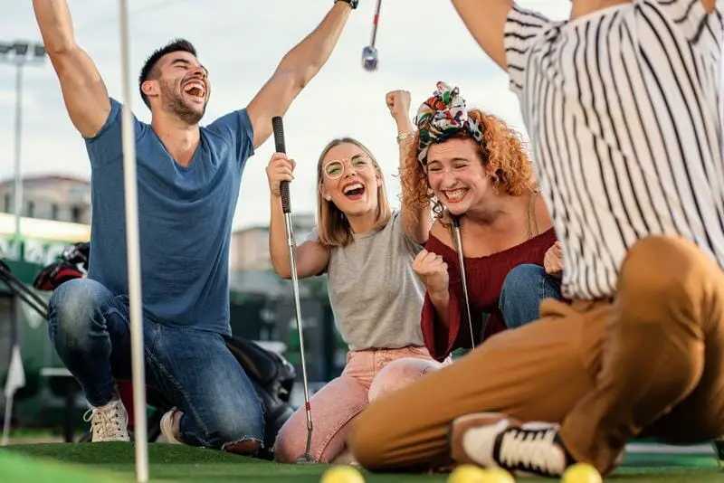 group of friends happily playing mini golf