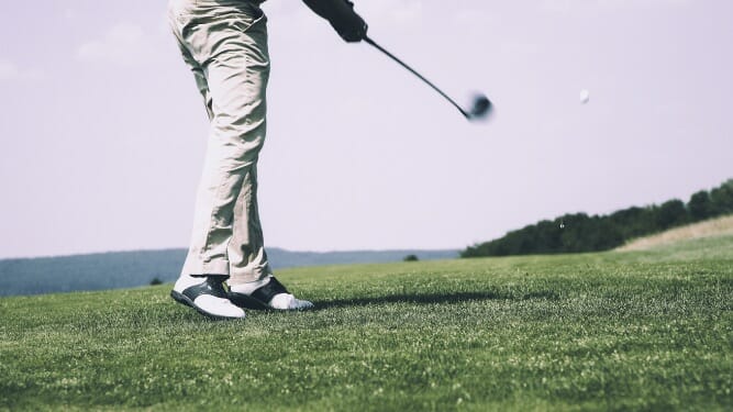 man hitting the ball in a golf field