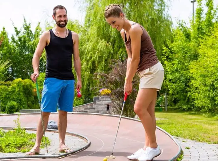 man and woman smiling playing mini-golf