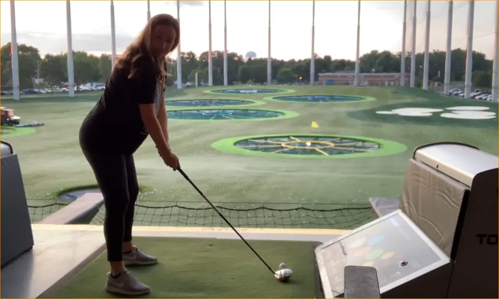 pregnant woman in all black playing golf