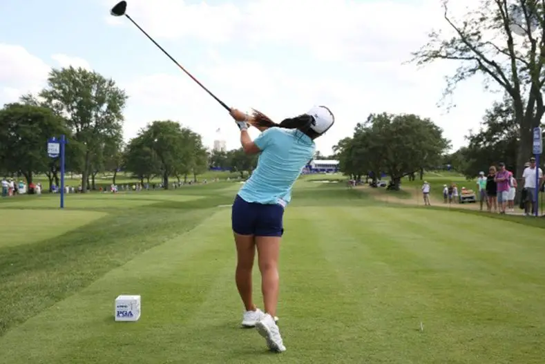 woman swinging and hitting the golf ball at the golf course